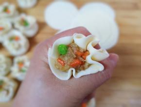 取一个加工好的烧麦皮放在手上，放上烧麦馅，把烧麦放在虎口处，大拇指和食指往里收一下，一个烧麦就包好了。