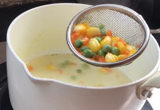 再把青豆、玉米粒和一半的胡萝卜碎放入锅中煮熟，捞出备用