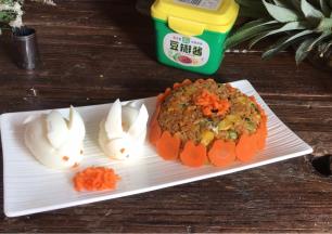 倒扣在盘中，摆上小白兔和萝卜碎，把胡萝卜兔摆在米饭周边