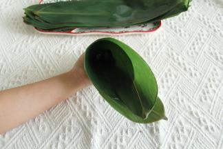 粽叶两张反向叠起，比较毛的两面贴合，宽的部位在两头。右边1/3处往里折成漏斗型。