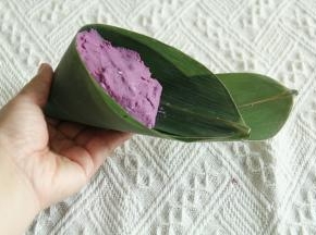 上面填上芋泥紫薯混合馅料。压平，不要超过粽叶边。