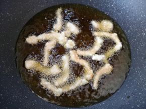 锅里倒多一些食用油烧至6成热，将里脊肉一根一根下入油锅，炸至淡黄色捞出。
