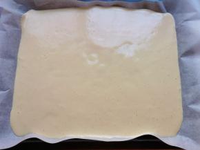 烤盘里铺上油纸，倒入混合好的蛋糊，轻震几下烤盘将蛋糊颠平。