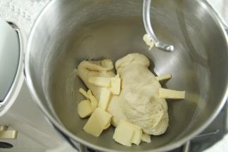 3、一档混合成团，转4-5档打至略光滑状态。轻轻扯开，粗膜状态，放入软化好的黄油。