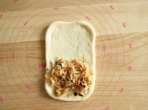 7、取一面团，按扁擀开成长方形，翻面整理。底部1/2抹上沙拉酱，放肉松。