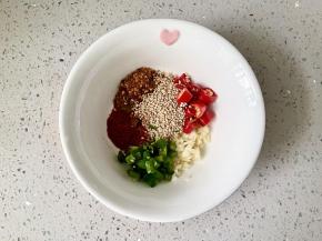 碗中放入小米椒圈，葱花，蒜末，白芝麻，辣椒面，辣椒粉