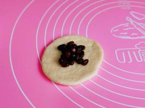 取一个面团擀开，放上蜜豆包起来，收口捏紧朝下揉圆。