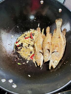 把鱼扒到一边，放入生姜，蒜瓣，花椒，干辣椒，豆豉爆香！