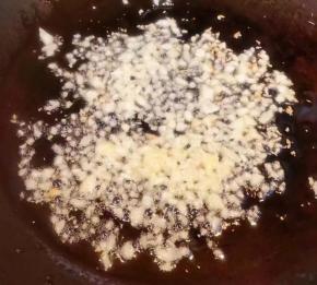 另起锅倒入底油加热放入蒜粒爆香