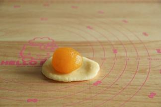 8、花型取18克皮，凤梨形取15克皮。饼皮搓圆放手心，用另一手按压成圆形，放入馅料球。