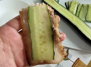 取一块五花肉肉片，再取一片黄瓜放在上面！