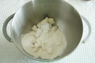 发好的种面体积变2-2.5倍大，拉起成蜂窝状（也可以室温不超过28度发到同样状态）切成小块，放入打面桶。加入主面团除黄油以外的材料，一档混合，转4挡打到粗膜阶段。（夏天温度高，加冰袋控制面温）