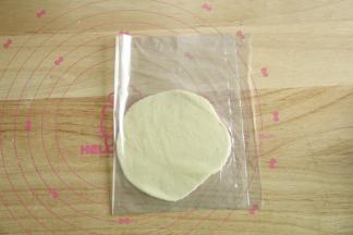 酥皮分28克一个。搓圆放在保鲜袋一侧，保鲜袋对折，用擀面杖轻轻擀成圆形