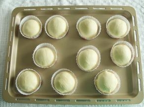 撕开保鲜袋，取下酥皮，放上滚圆的面团，光滑面接触酥皮。然后将酥皮贴合到面团底部，略收紧即可。放入圆形油淋模具中，排入烤盘。