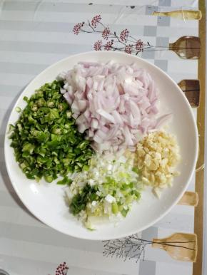 烤肉夹馍饼胚的时候我们来准备夹在饼胚里的馅料儿：
青椒去蒂洗净切成小丁，洋葱洗净切成小丁，蒜瓣切成末，葱切成葱末备用！