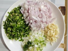 烤肉夹馍饼胚的时候我们来准备夹在饼胚里的馅料儿：
青椒去蒂洗净切成小丁，洋葱洗净切成小丁，蒜瓣切成末，葱切成葱末备用！