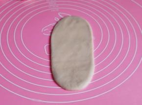 取一个面团擀长舌状卷起来。