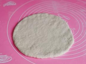 取一块面团擀成和披萨盘同样大小的圆饼。