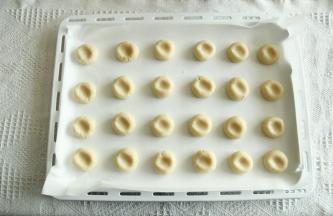 预热烤箱，上下180度。带PVC手套，分团15克一个，搓圆排列在垫了油纸的烤盘上，用大拇指从中间轻轻按扁。