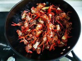 锅中倒油，比炒菜时的油多一倍，油热倒入配料爆香，再倒入小龙虾翻炒均匀，