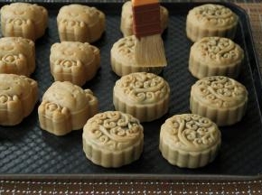 用羊毛刷蘸取蛋液，在边刮干净（新手可以把蘸好蛋液的毛刷放在油纸上，用刮板轻轻刮一下，刮去多余的蛋液），然后快速的在月饼表面刷上蛋液，刷2下，不要反复刷多了。上色过重，成品回油后看着比较黑。