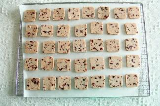 预热烤箱上下170度。冻好的饼干胚取出回温5分钟，切成0.8厘米均匀厚片。排列在垫了油纸的烤网或者烤盘上。