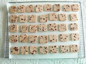 预热烤箱上下170度。冻好的饼干胚取出回温5分钟，切成0.8厘米均匀厚片。排列在垫了油纸的烤网或者烤盘上。