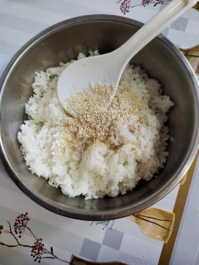 加一点寿司醋（没有寿司醋也可以不加，不影响口味！），放一点食用油，熟白芝麻，适量的香油！（寿司醋，熟白芝麻，香油和食用油适量就可以了！不要放的太多，太多的话，它就掩盖了我们米饭的香气！加食用油只是为了让我们的米饭看起来更加的晶莹剔透，铺米饭的时候比较好铺！它不容易粘米！香油和寿司醋只是为了调节米饭的味道，千万不要太多啊，适量就可以了！）