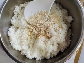 加一点寿司醋（没有寿司醋也可以不加，不影响口味！），放一点食用油，熟白芝麻，适量的香油！（寿司醋，熟白芝麻，香油和食用油适量就可以了！不要放的太多，太多的话，它就掩盖了我们米饭的香气！加食用油只是为了让我们的米饭看起来更加的晶莹剔透，铺米饭的时候比较好铺！它不容易粘米！香油和寿司醋只是为了调节米饭的味道，千万不要太多啊，适量就可以了！）