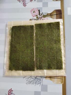 寿司海苔对半切开，毛糙的那一面朝上，放在寿司帘上！