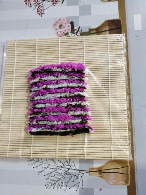 把切好的条，侧面立起来平铺在寿司帘上，稍微往中间挤压一下，让它更紧实一些！