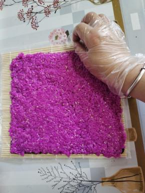 把拌好的红色米饭均匀的平铺在海苔上，按压紧实！