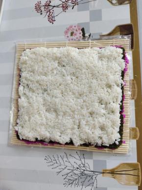 翻面，把寿司海苔反转过来，再把拌好的白米饭均匀的平铺在海苔上！按压紧实一些！