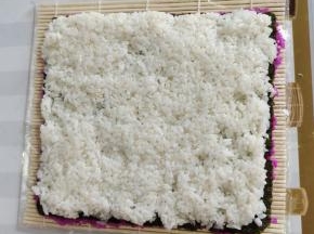 翻面，把寿司海苔反转过来，再把拌好的白米饭均匀的平铺在海苔上！按压紧实一些！