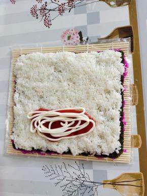 在整张海苔的下方三分之一处留两指的位置，正中间位置挤上适量的番茄酱和沙拉酱！