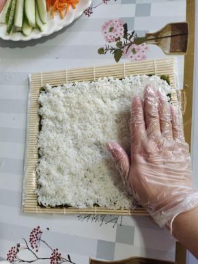 左手固定住海苔，右手手掌根部向上，按，推滑米饭！往下的时候用手指肚向下按，推滑米饭！