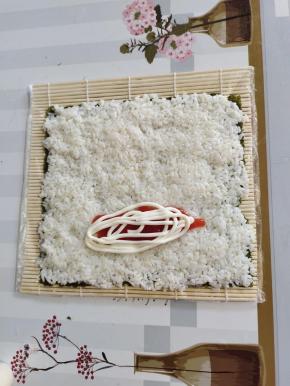 在海苔下方三分之一留两指的位置挤上适量的番茄酱和沙拉酱！