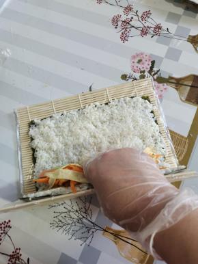 把食材放在下三分之一的位置！不能放到边上卷不起来！也不能放的太往上，卷起来会比较松散！手一定是扶住食材，往里收！收的越紧卷的越紧！拇指虎口夹住我们的卷帘往上翻！翻到下面我们需要用力的往下按压，捏！这一步是很重要的！