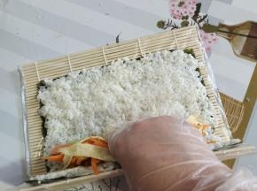 把食材放在下三分之一的位置！不能放到边上卷不起来！也不能放的太往上，卷起来会比较松散！手一定是扶住食材，往里收！收的越紧卷的越紧！拇指虎口夹住我们的卷帘往上翻！翻到下面我们需要用力的往下按压，捏！这一步是很重要的！