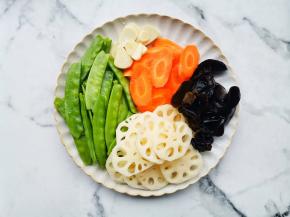 莲藕去皮切片、胡萝卜切片、木耳温水泡发，荷兰豆洗净去茎，蒜切片。