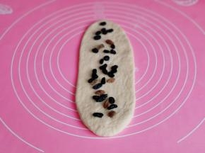 取一块面团擀长舌状，撒上葡萄干。