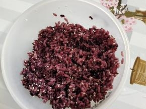 蒸熟的紫米饭打散，放入适量的熟白芝麻，食用油和香油，寿司醋适量搅拌均匀！晾至温热！