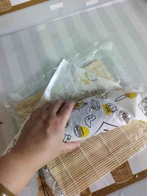 把包装纸的头塞到海苔的下面！然后去给它卷一下！（左手按住，右手往回拉！再往前卷一下，再按一下给它定一下型！！拉的时候要轻轻的，不要用蛮力，会容易碎！）