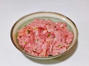 肉糜放入器具中，加入切好的葱姜蒜末顺时针搅拌。