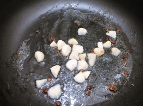 锅里倒入适量植物油，放入大蒜粒和花椒炒香