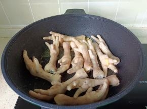 锅里加入生姜片，蒜末炒香，放入凤爪。