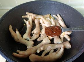 把凤爪翻炒至两面金黄色，加黄豆酱一勺。