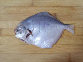 用刀在鱼的两面各划几道，放入盘子里。 