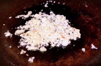 另起锅倒入底油加热放入蒜粒爆香