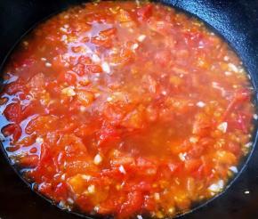 锅中倒入底油加热放入蒜粒爆香再放入切好的番茄炒碎出汤汁添加适量清水烧开